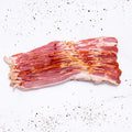 Several strips of Applewood Bacon are arranged neatly on a white surface, surrounded by scattered black pepper and seasoning.