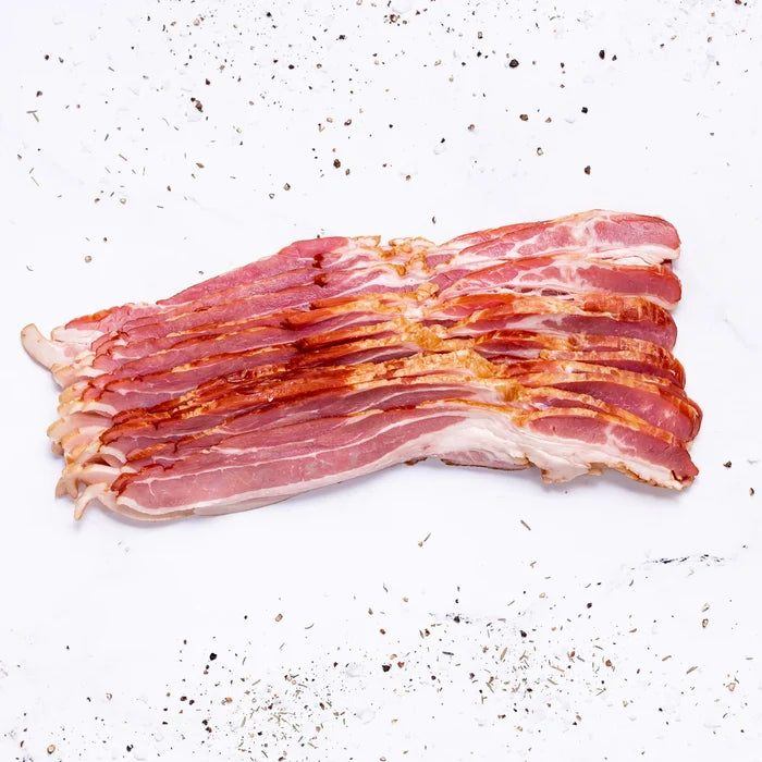 Several strips of Applewood Bacon are arranged neatly on a white surface, surrounded by scattered black pepper and seasoning.
