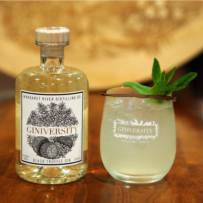 Giniversity Black Truffle Gin 700ml bottle next to a Giniversity gin glass with a G&T and chocolate and mint as a garnish