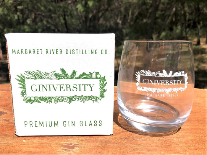 Giniversity gin glass box next to Giniversity gin glass. Box is white with Giniversity logo and Margaret River printed in green. Gin glass has Giniversity logo and Margaret River printed in white