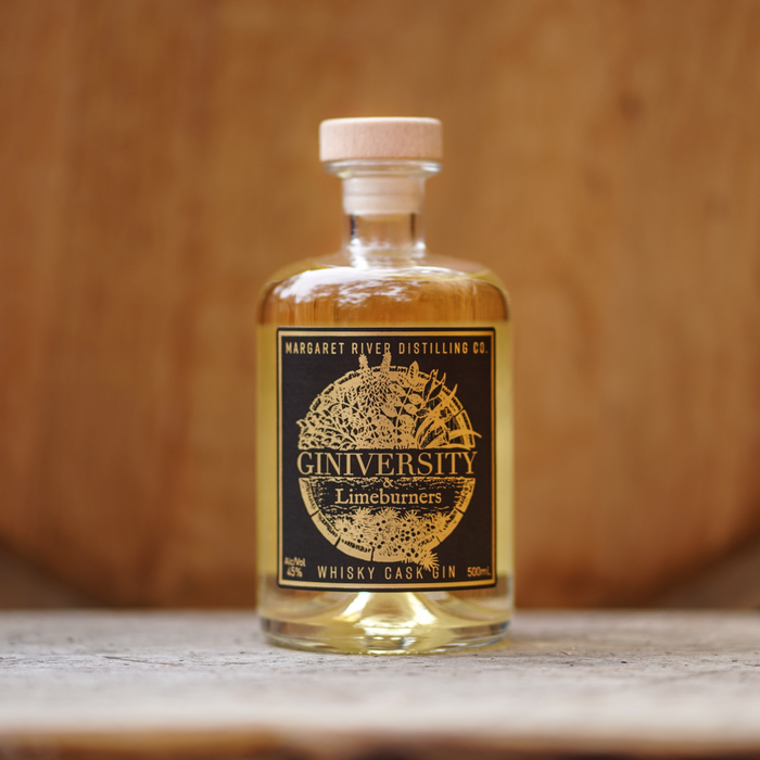 Giniversity whisky cask gin 500ml bottle with a barrel in the background