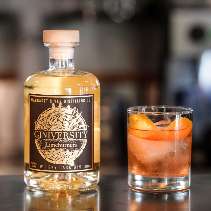 Giniversity Whisky Cask Gin 500ml bottle next to an old fashioned cocktail