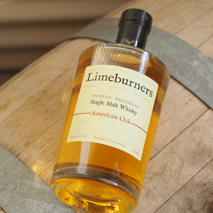 Limeburners American Oak 700ml bottle laying down on a whisky barrel