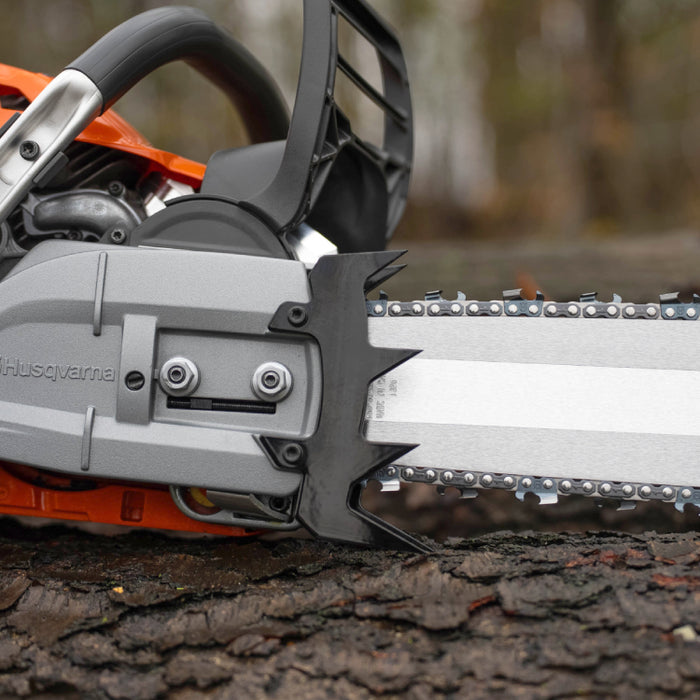 Ripsaw 4 Point Felling Dog installed on a Husqvarna 572 chainsaw, shown resting on a log with a forest background.